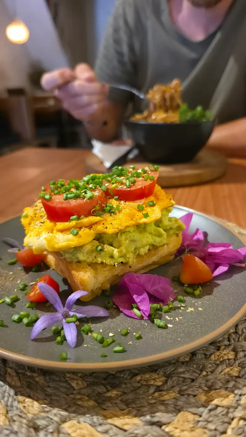 Avocado toast with scrambled egg, tomato and edible flowers