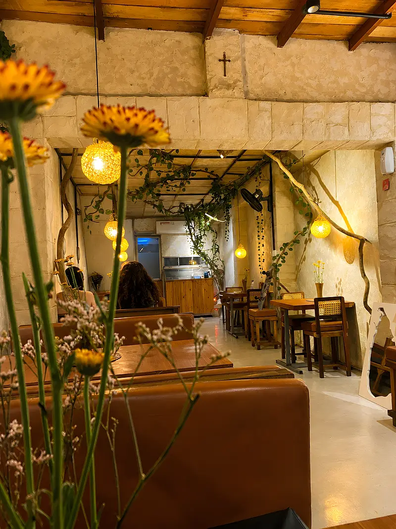 View past yellow gerberas into the dining room, with leather booths and a vine-wrapped wooden ceiling