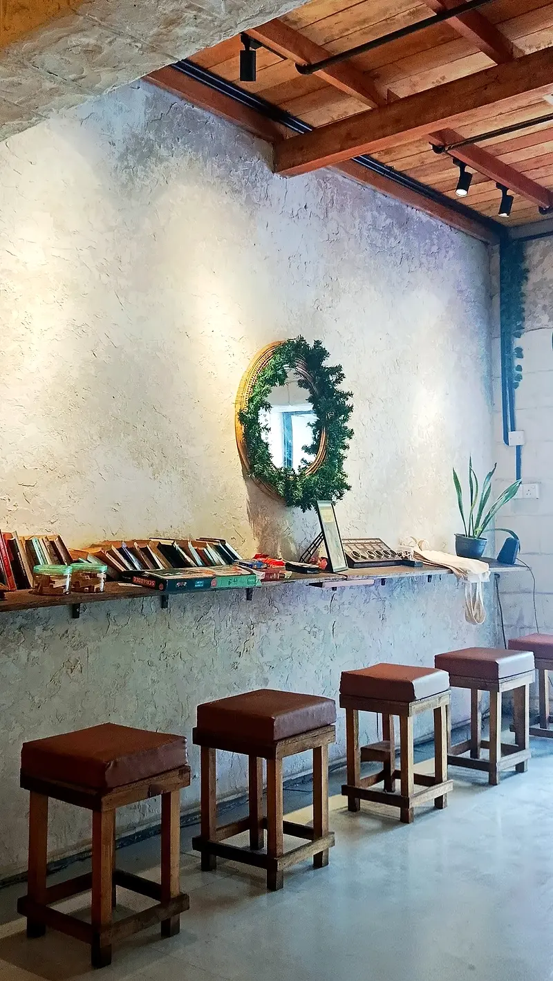 Window bar with leather stools, a shelf of books and a wreath-framed mirror