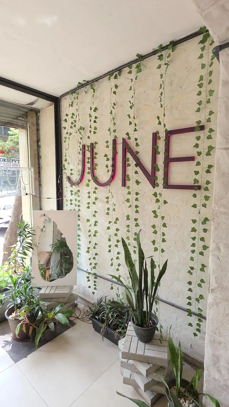 The word JUNE in plum lettering on a wall of hanging vines at the entrance
