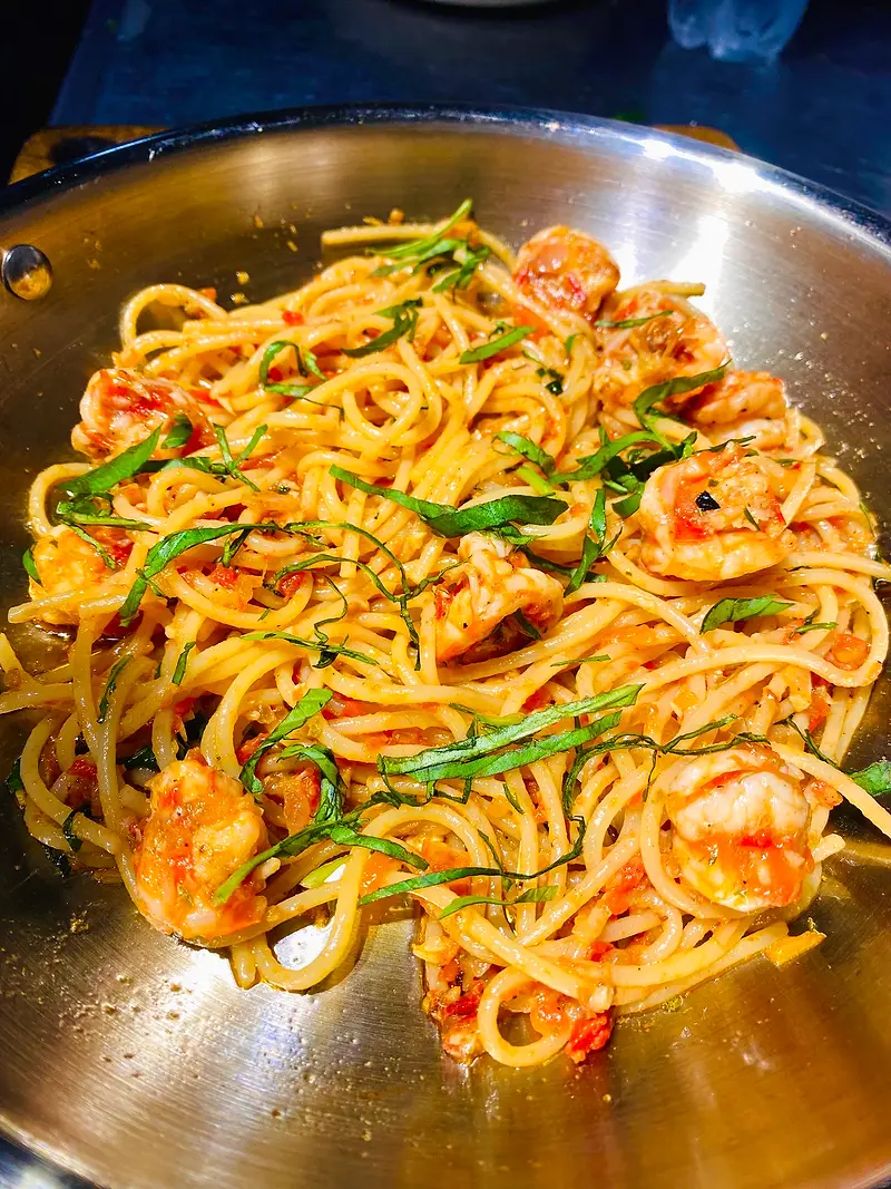 Prawn spaghetti tossed with tomato, chilli and herbs in a steel pan