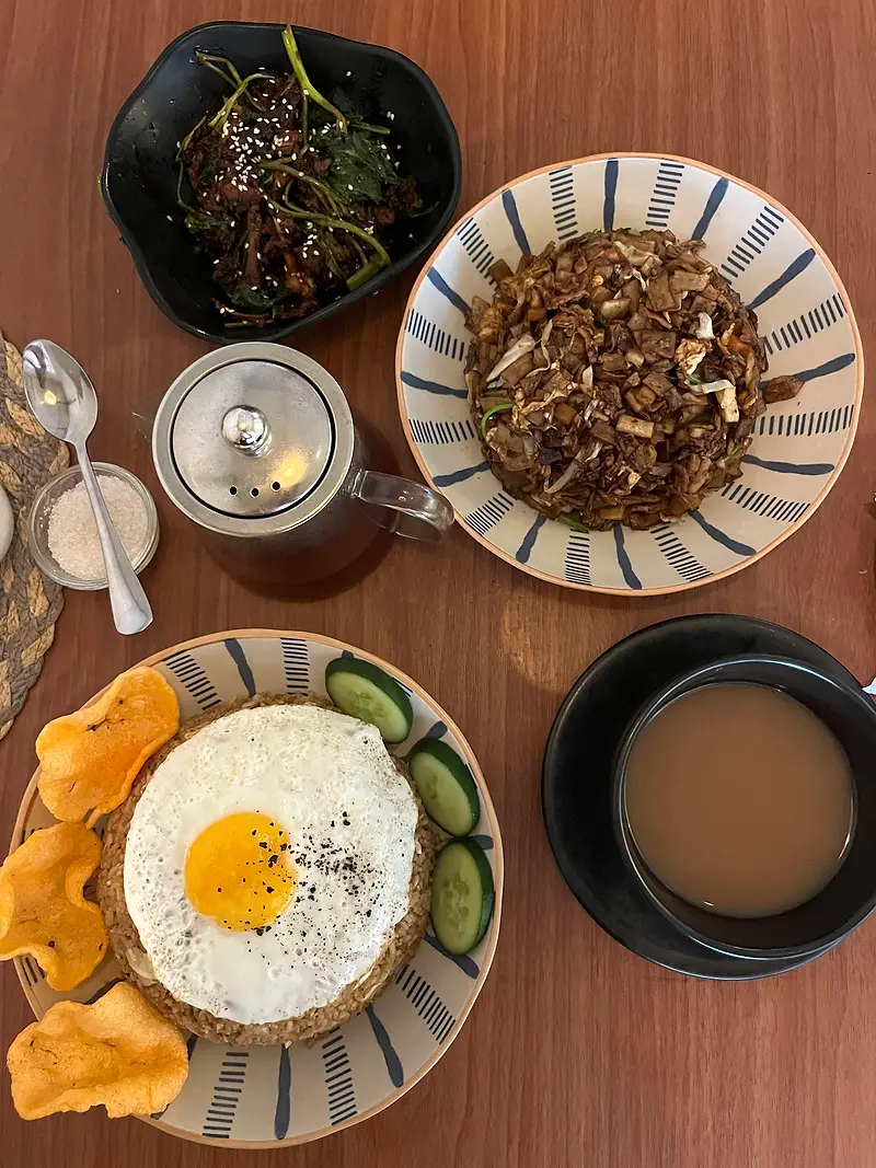 Rice bowls with a fried egg, crispy crackers, cucumber and a pot of tea, seen from above