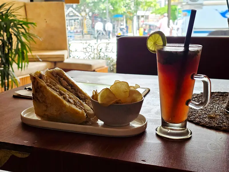 Toasted sandwich with chips and an iced tea with lime by the window