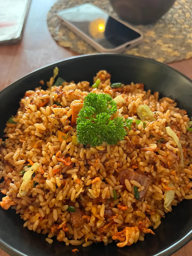 Sausage fried rice topped with parsley in a dark bowl