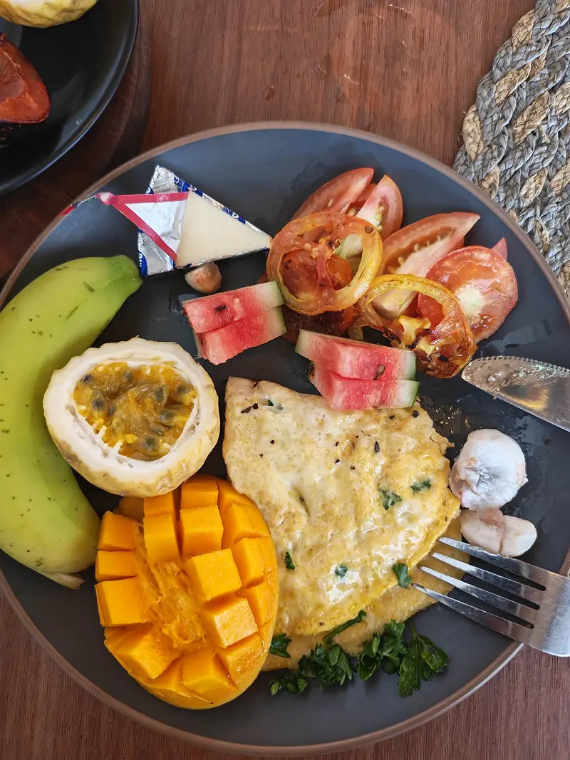 Breakfast plate with an omelette, mango, passion fruit, watermelon, banana and tomato